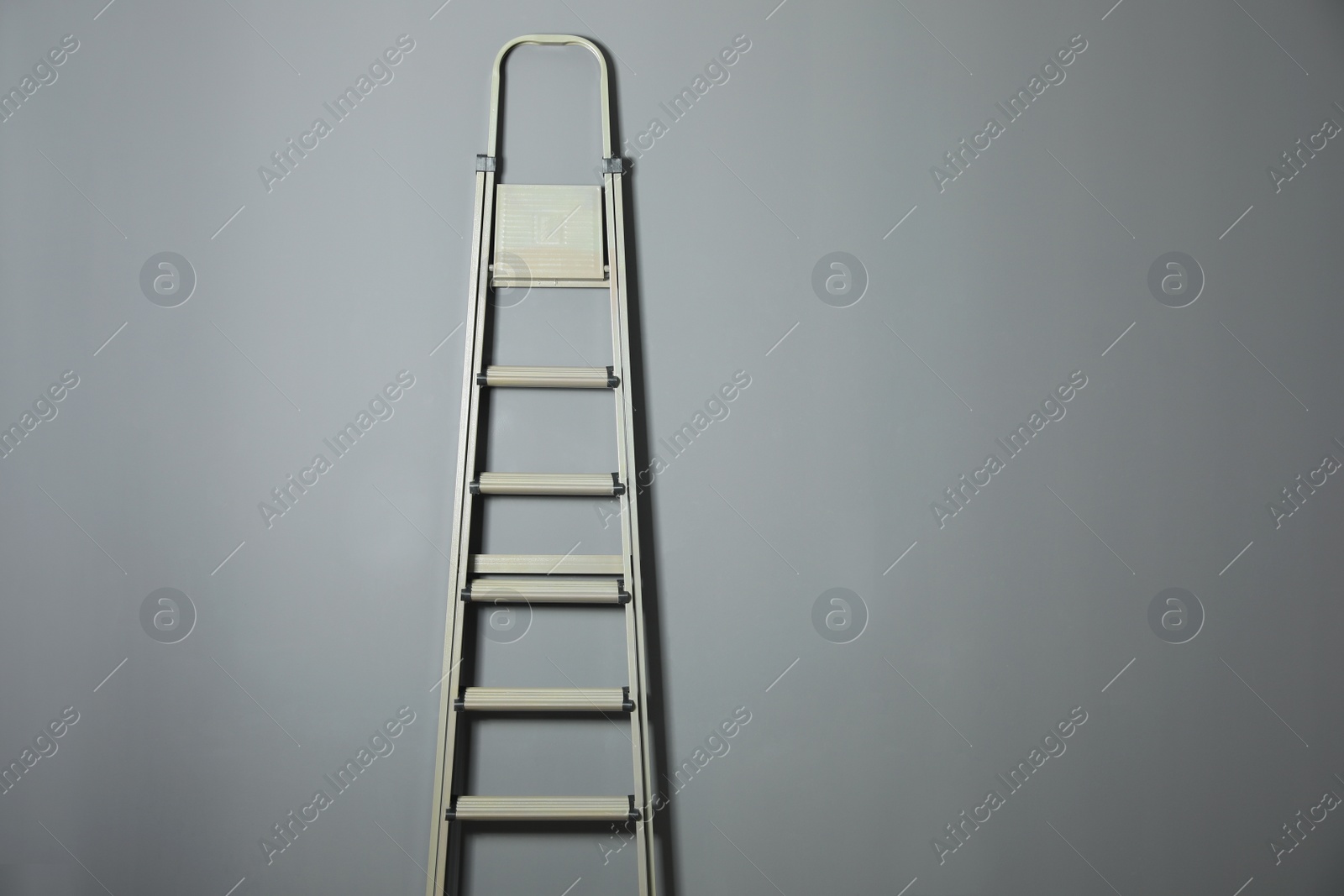 Photo of Metal stepladder on grey background. Space for text