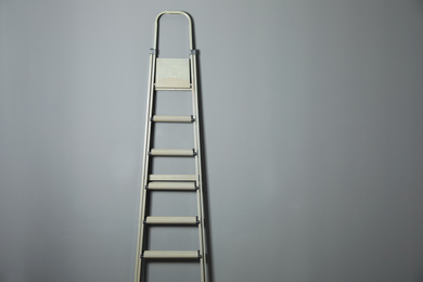 Photo of Metal stepladder on grey background. Space for text