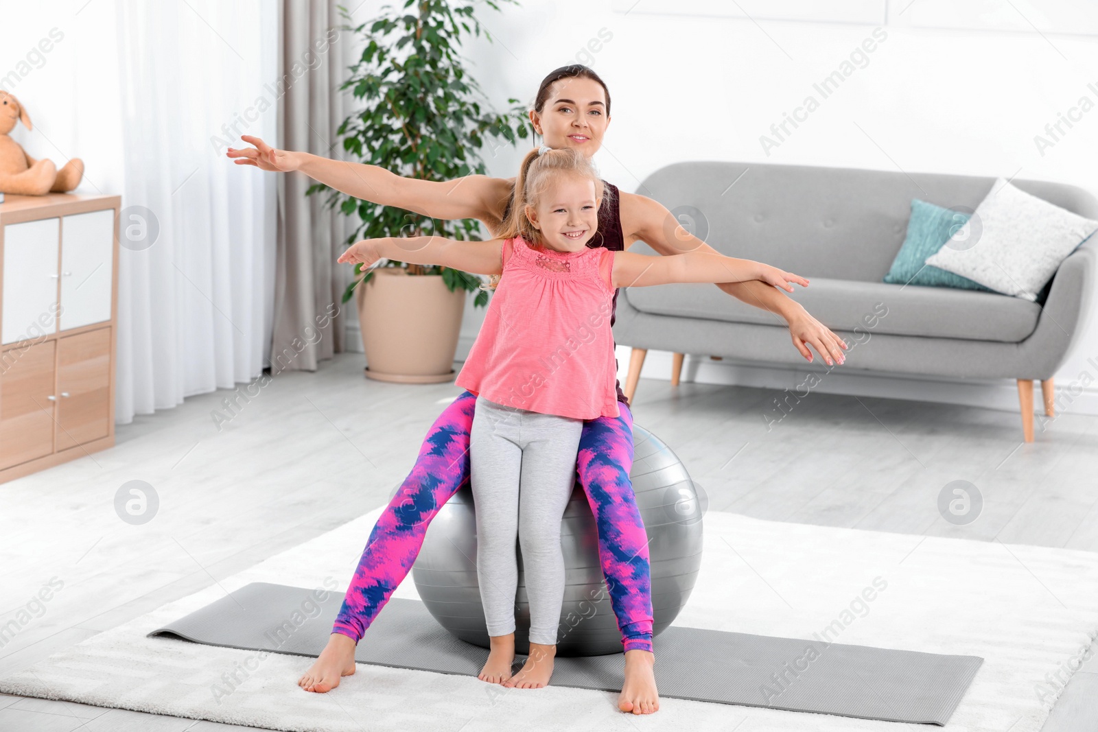 Photo of Sportive woman doing fitness exercises with daughter at home