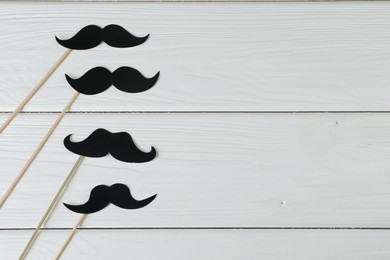 Photo of Fake paper mustaches party props on white wooden background, flat lay. Space for text