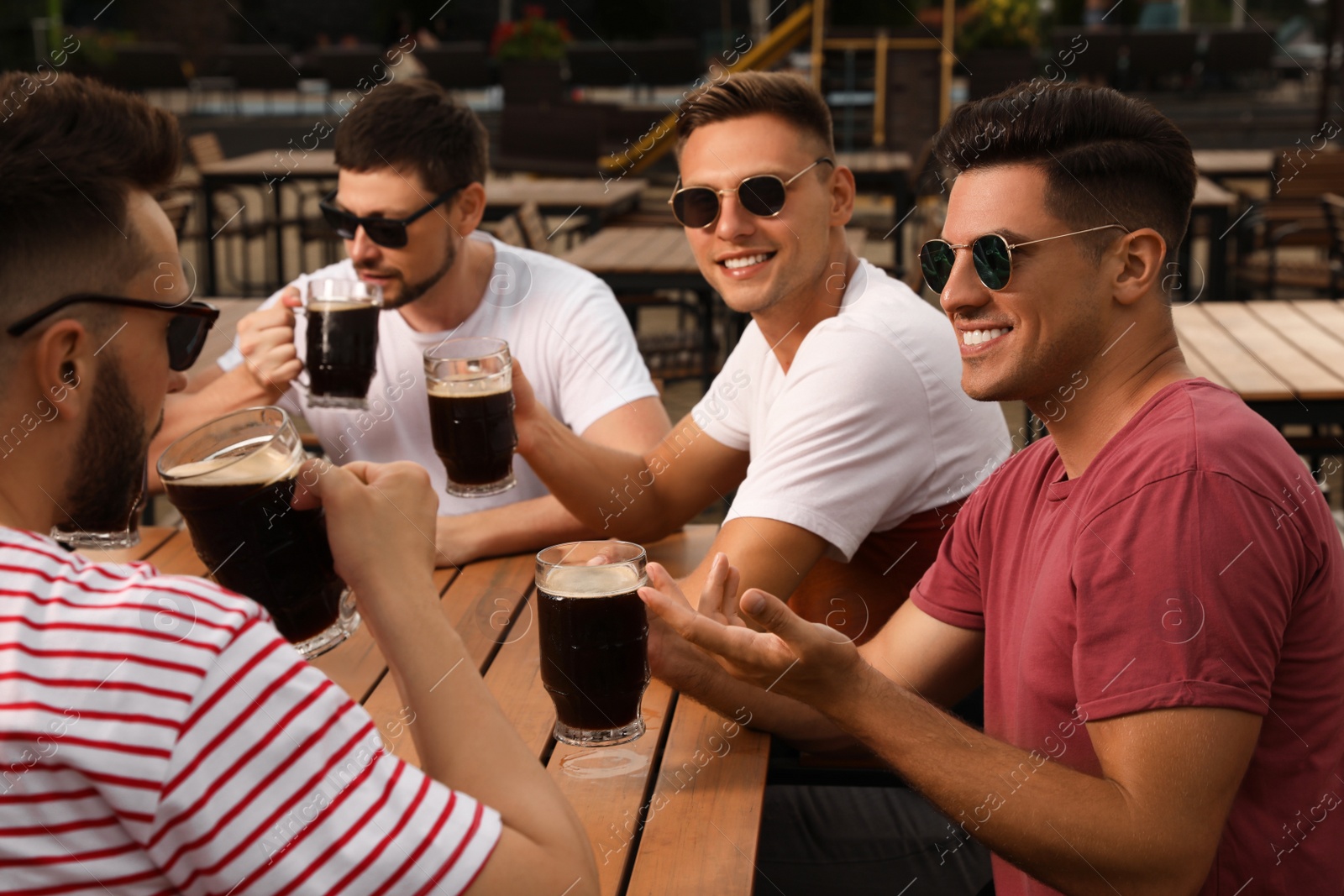 Photo of Friends with glasses of beer in outdoor cafe