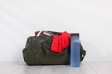 Photo of Gym bag and sports equipment on floor near white wall