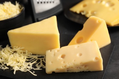 Grated and cut cheese on black table, closeup