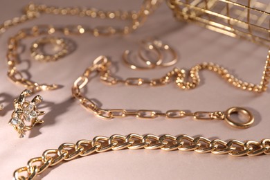 Photo of Metal chains and other different accessories on light brown background, closeup. Luxury jewelry