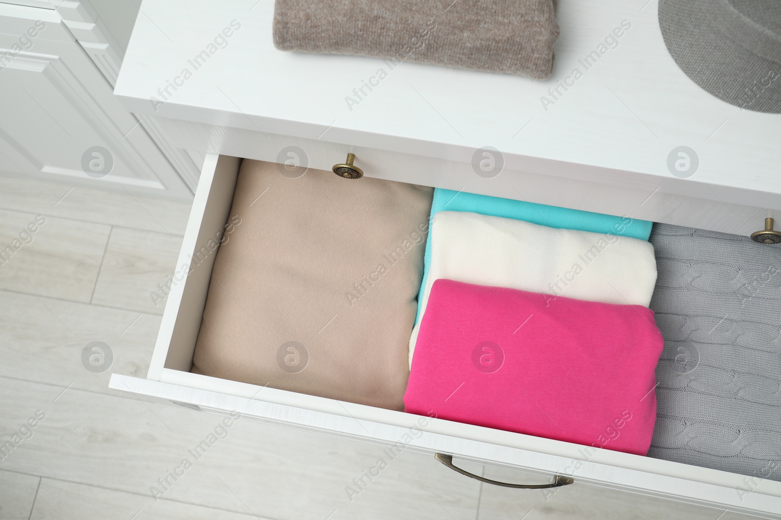 Photo of Chest of drawers with different folded clothes indoors, top view