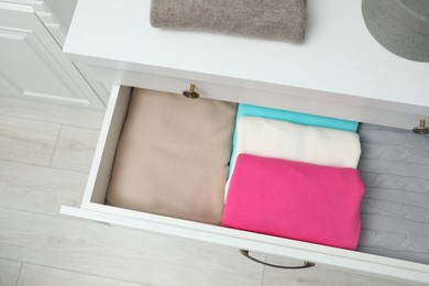 Chest of drawers with different folded clothes indoors, top view