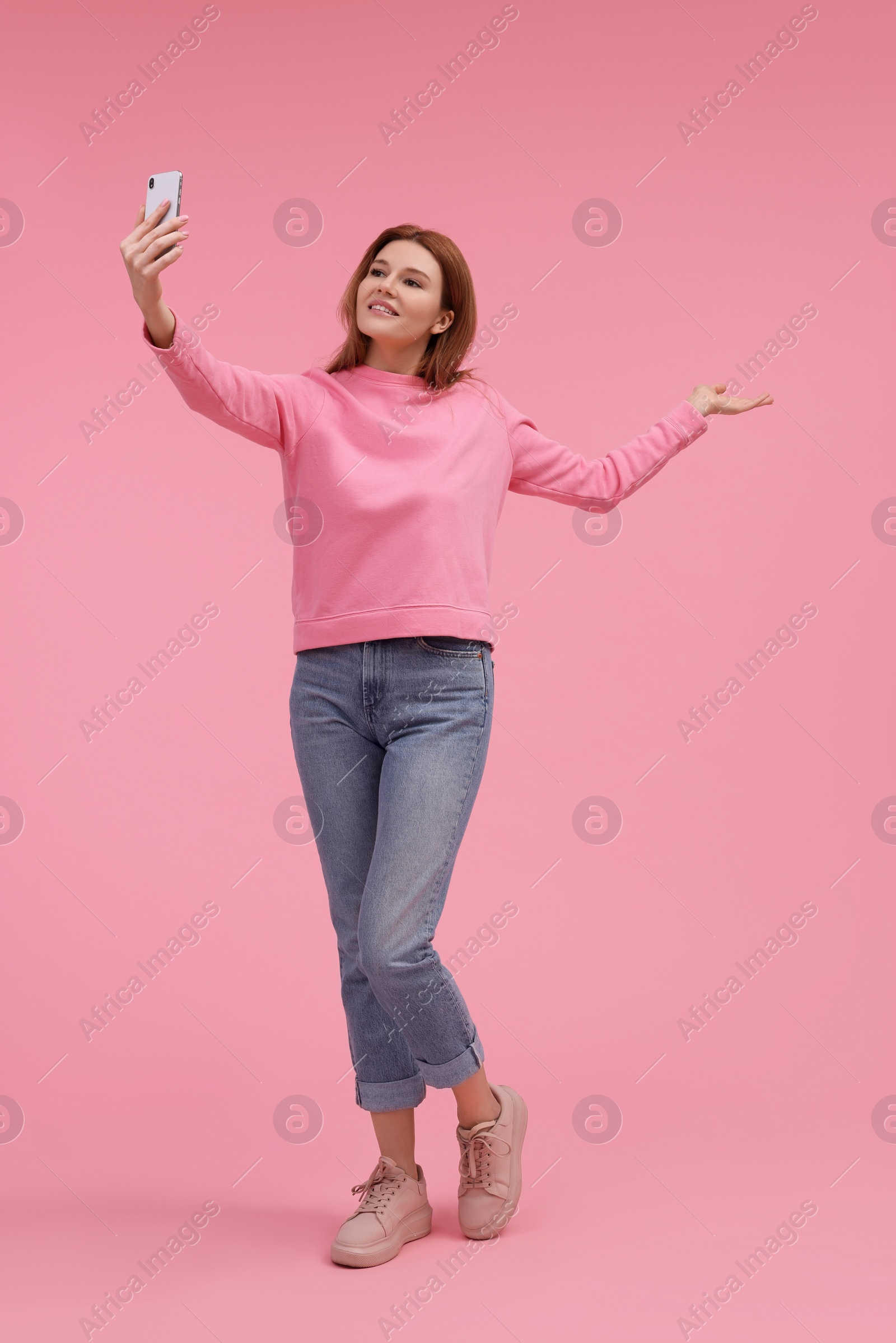 Photo of Beautiful woman taking selfie on pink background