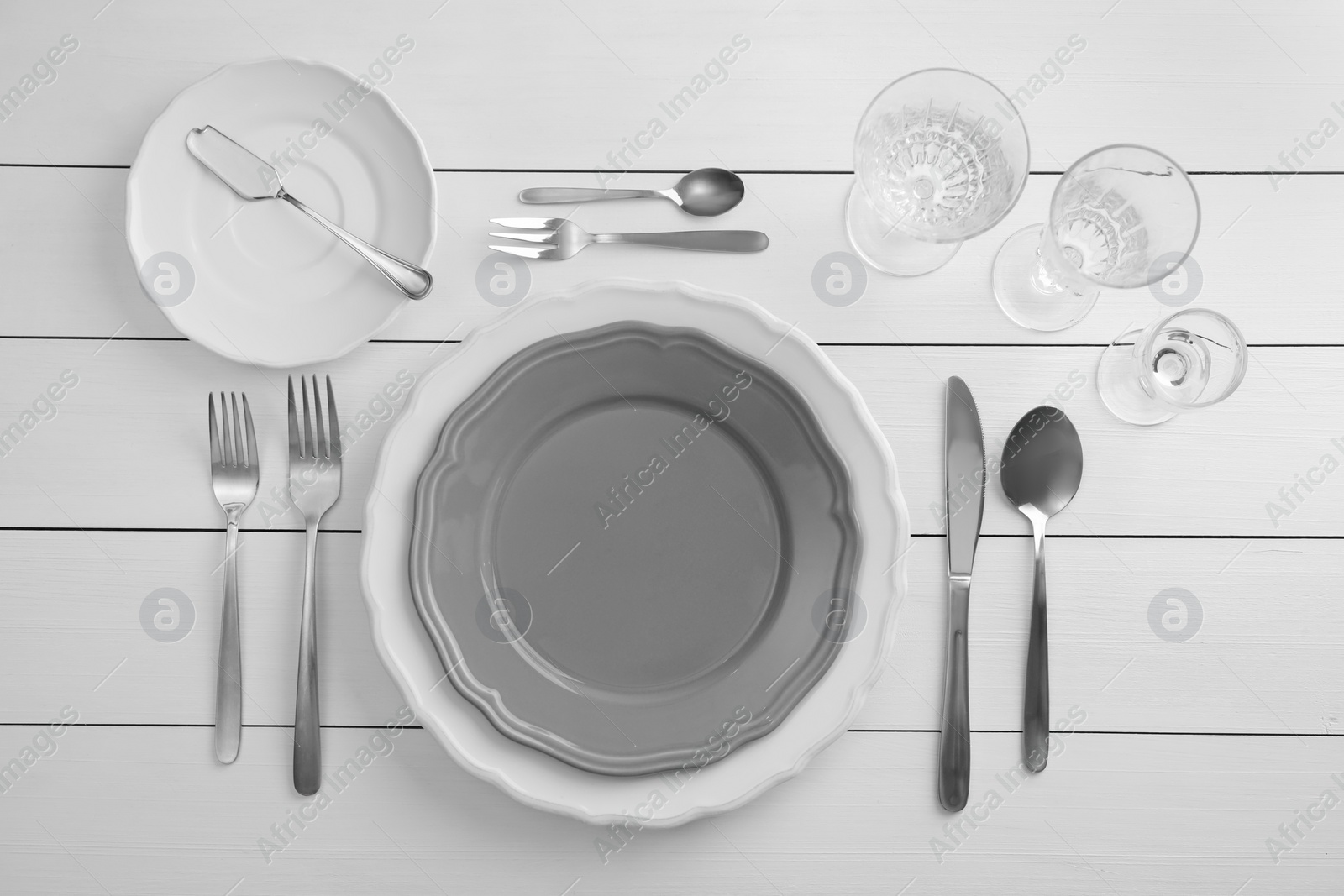 Photo of Stylish setting with cutlery, glasses and plates on white wooden table, flat lay