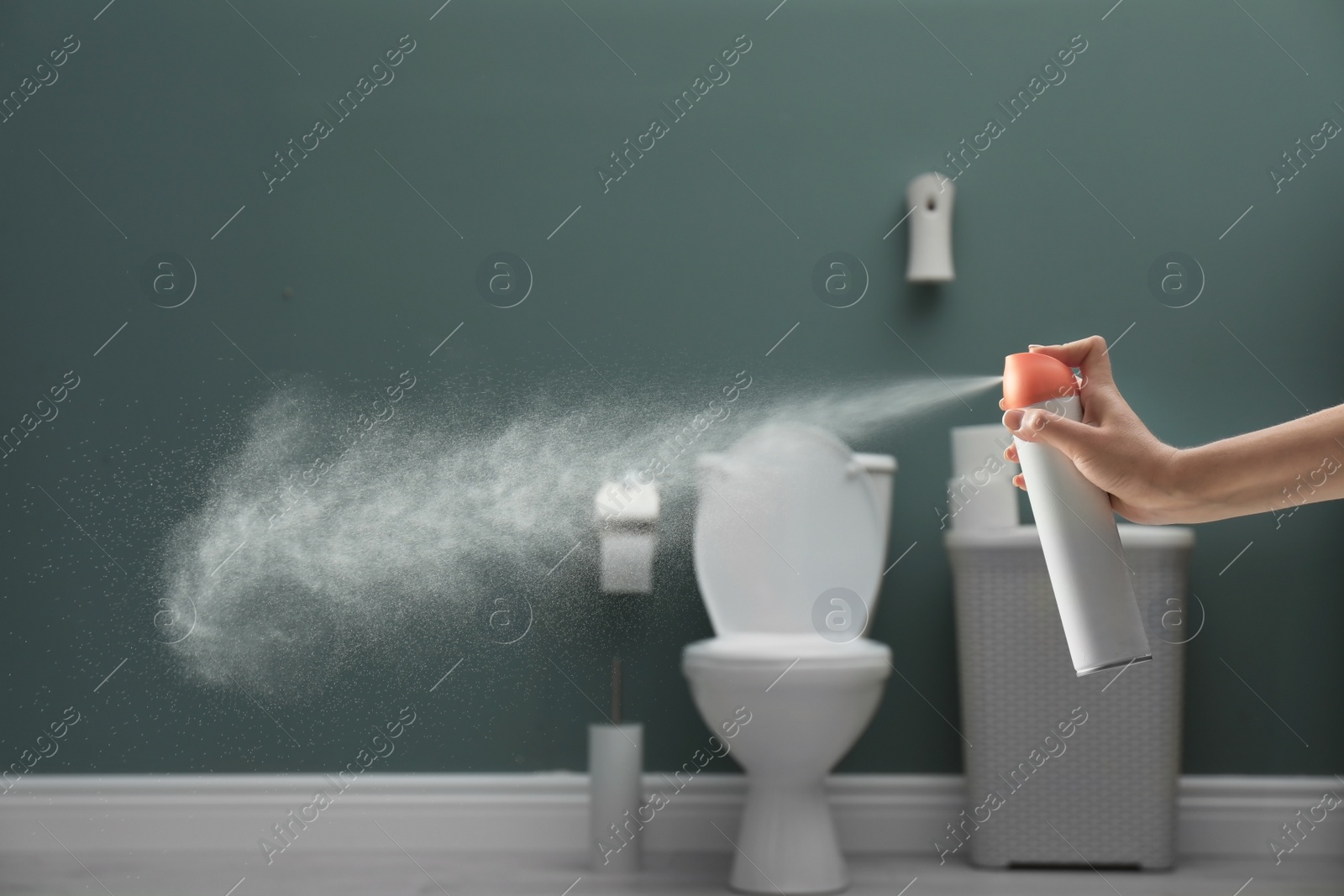 Photo of Woman spraying air freshener in bathroom