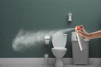 Photo of Woman spraying air freshener in bathroom