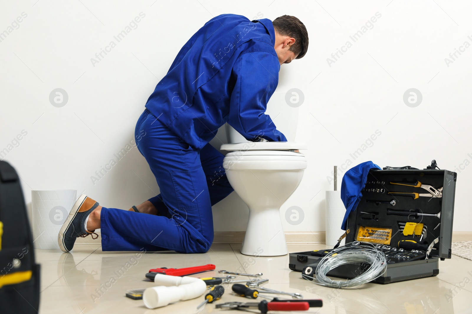 Photo of Professional plumber working with toilet bowl in bathroom