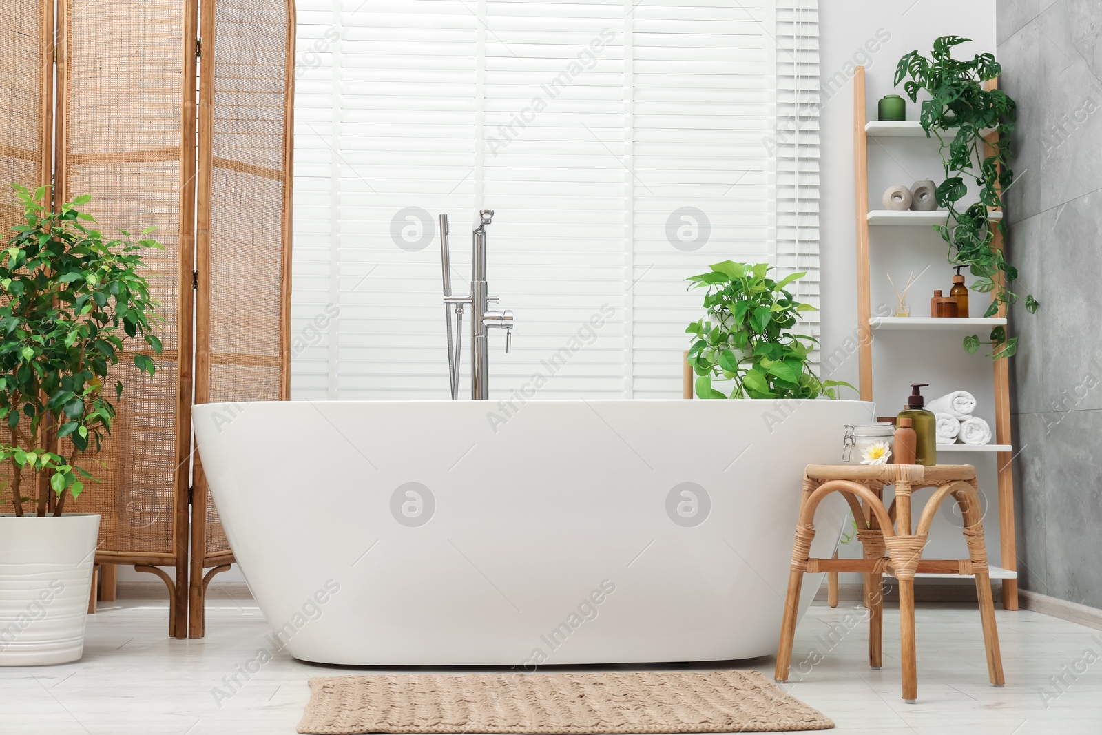 Photo of Spa day. Stylish bathroom interior with ceramic tub and green houseplants