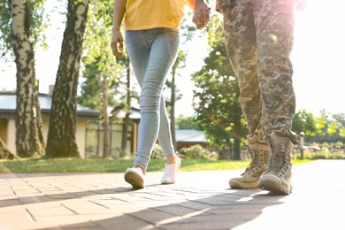 Man in military uniform walking with his girlfriend at sunny park, closeup