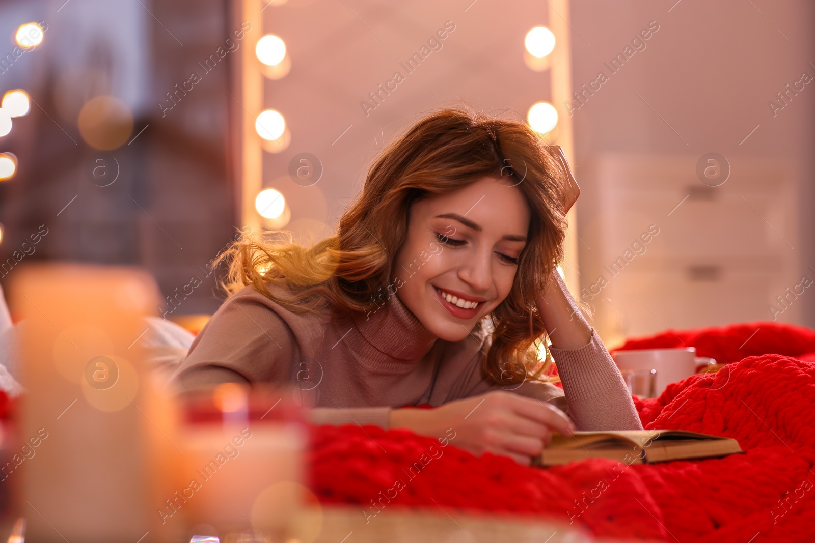 Photo of Beautiful young woman with book relaxing on bed at home. Cozy atmosphere