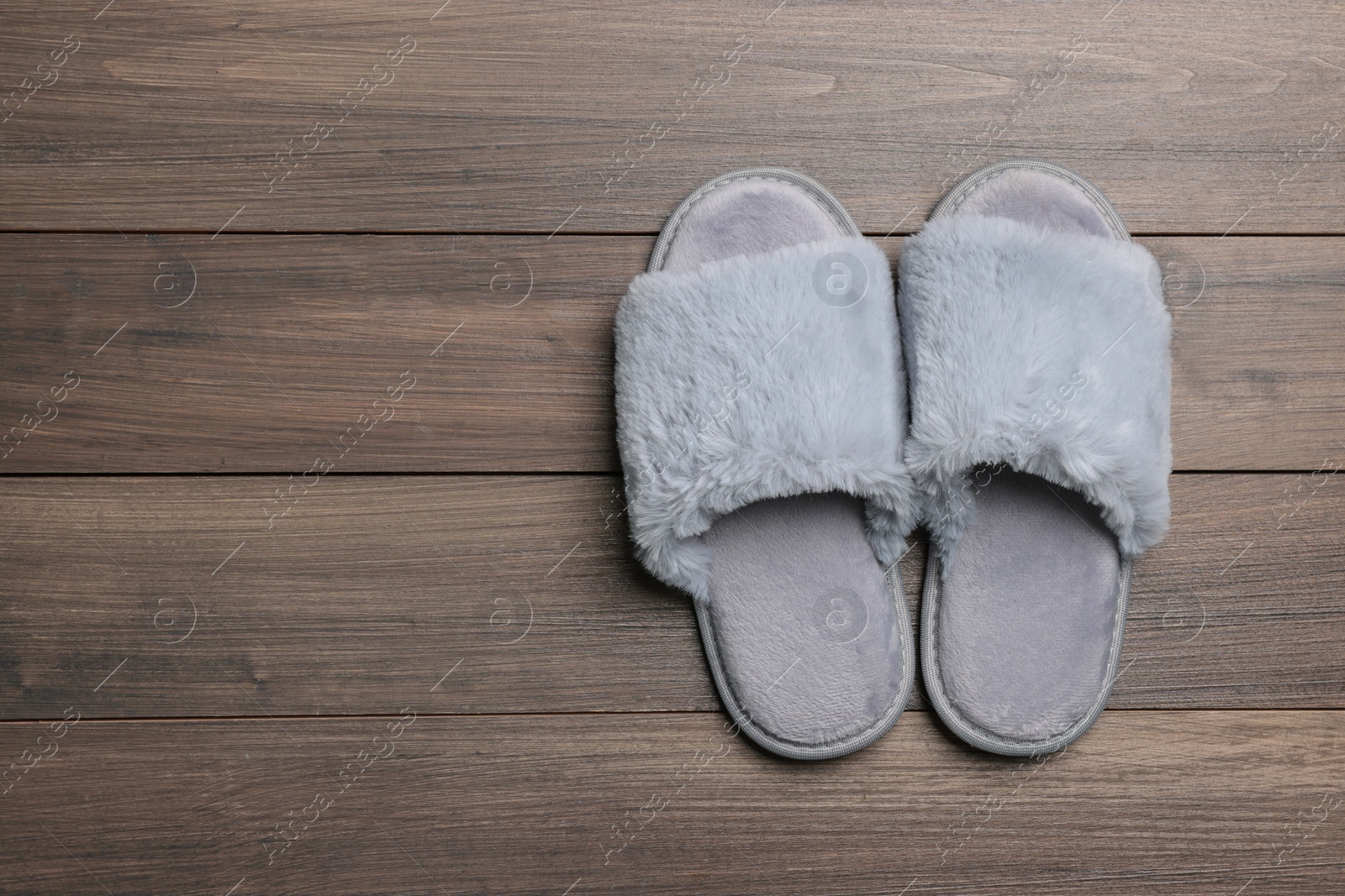 Photo of Pair of soft slippers on wooden floor, top view. Space for text