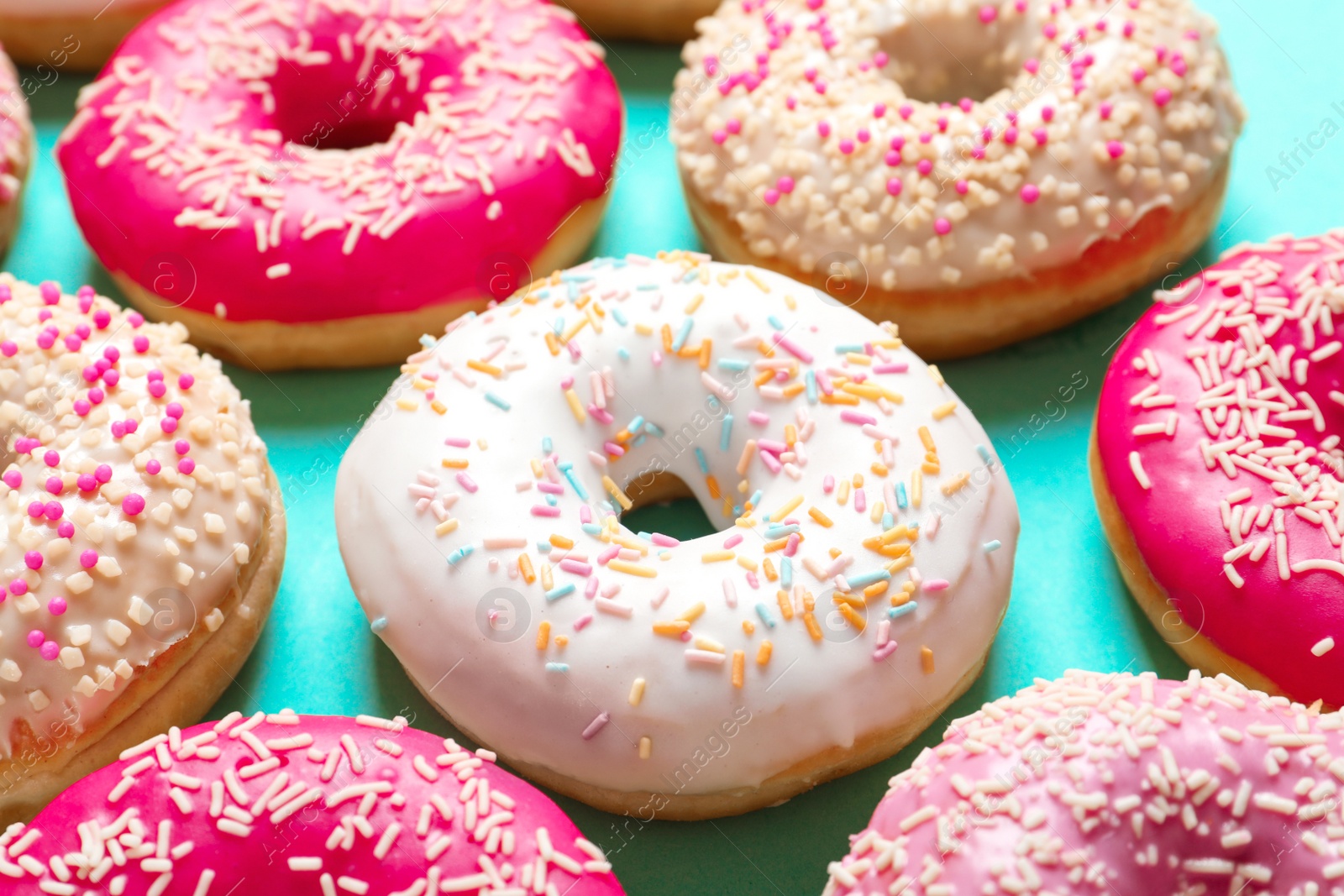 Photo of Delicious glazed doughnuts with sprinkles on color background