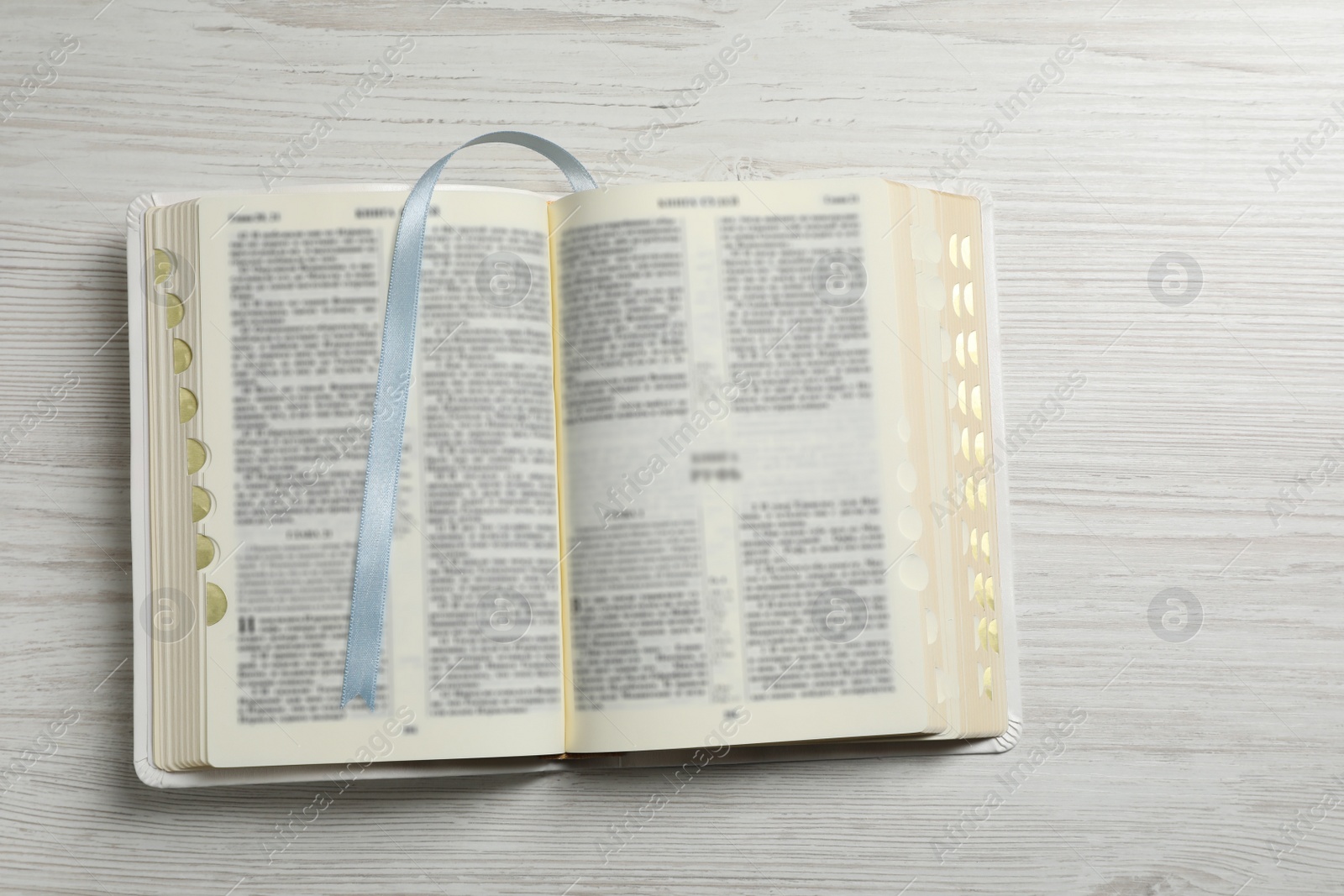 Photo of Open Bible on white wooden table, top view. Christian religious book