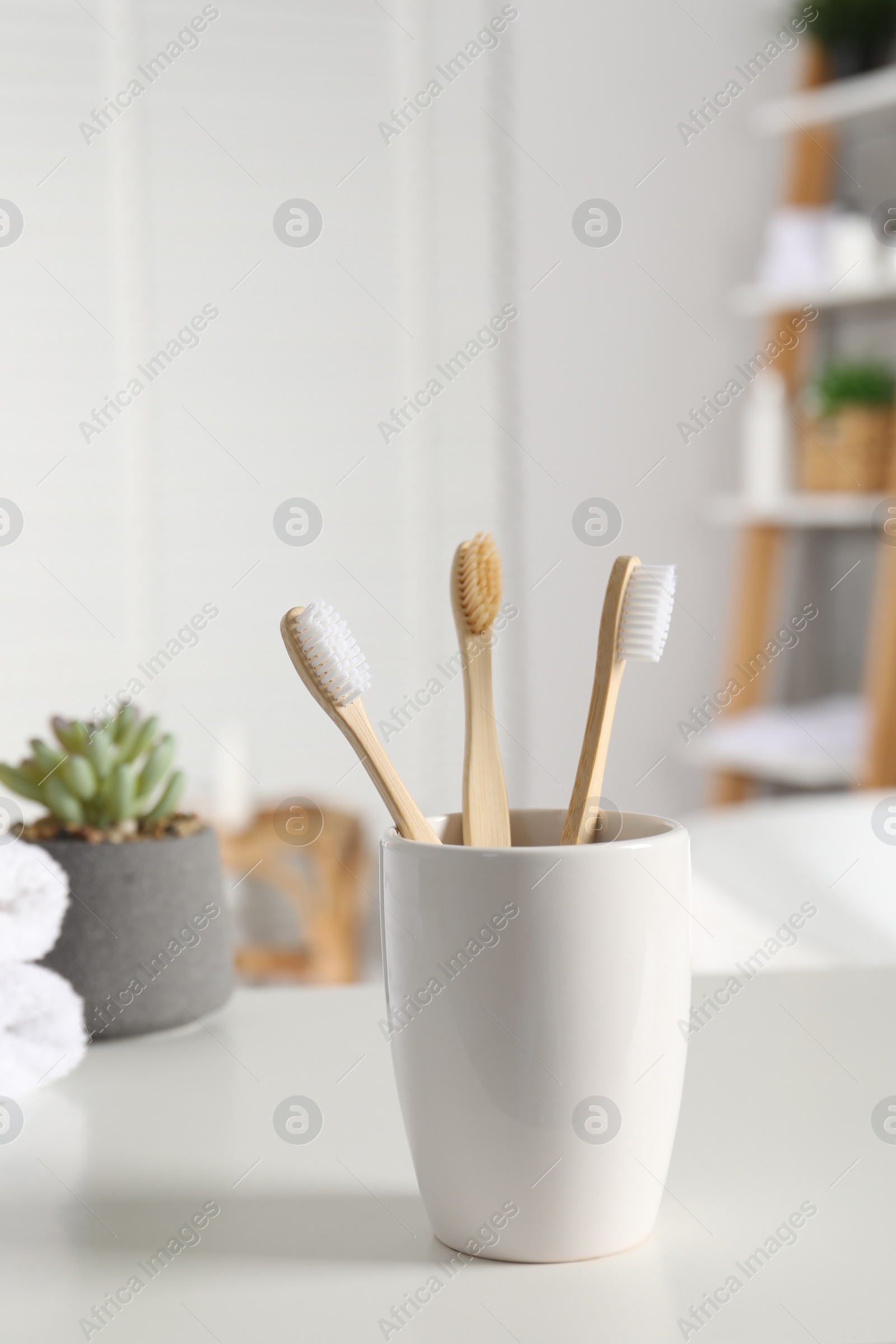 Photo of Holder with bamboo toothbrushes on white countertop in bathroom