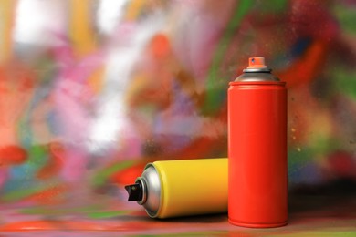 Photo of Cans of different graffiti spray paints on color background, space for text