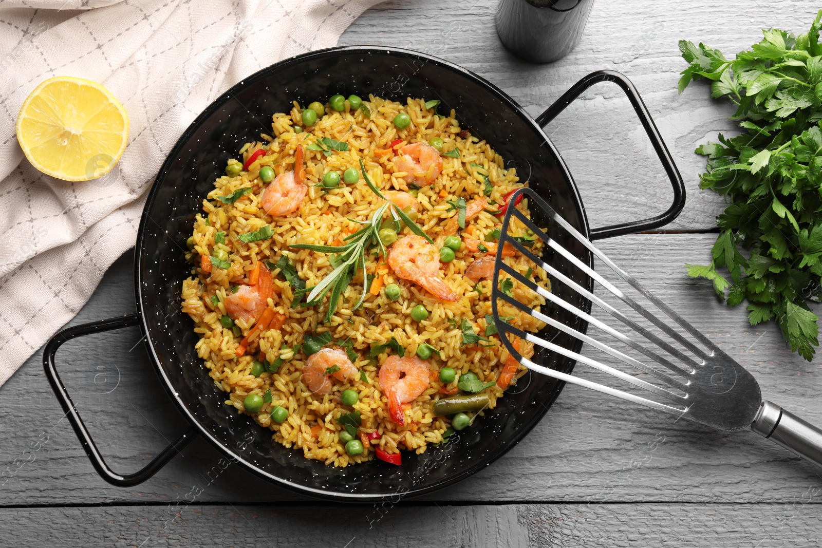 Photo of Tasty rice with shrimps and vegetables served on grey wooden table, flat lay