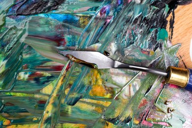 Photo of Abstract colorful acrylic paint and spatula, top view