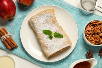 Delicious strudel with apples and ingredients on white table, flat lay