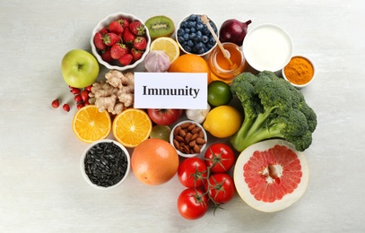 Photo of Card with phrase Immunity and fresh products on light table, flat lay