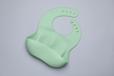 Green silicone baby bib on grey background, top view. First food