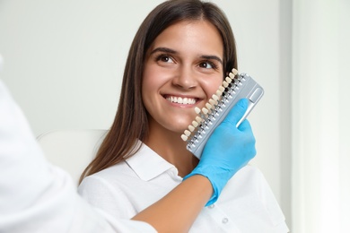 Photo of Doctor checking young woman's teeth color in clinic. Cosmetic dentistry
