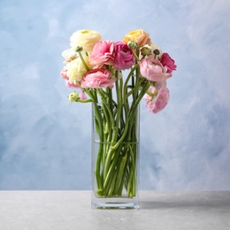 Photo of Beautiful ranunculus flowers in glass vase on table
