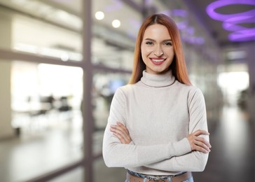 Portrait of happy woman in office. Pretty girl looking at camera and smiling on blurred background, space for text