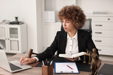 Notary with notebook using laptop at workplace in office