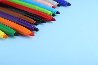 Photo of Many different colorful markers on light blue background. Space for text