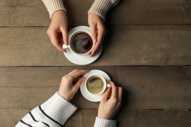 Photo of Women with cupsaromatic coffee at wooden table, top view. Space for text