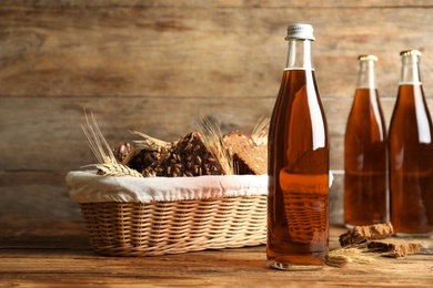 Photo of Bottles of delicious fresh kvass, spikelets and bread on wooden table