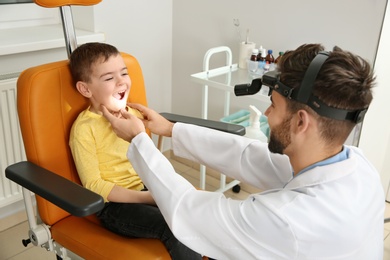 Photo of Professional otolaryngologist examining little boy in clinic