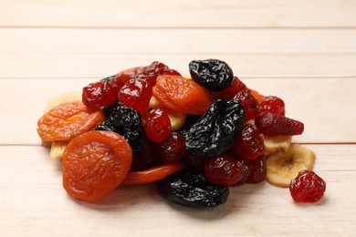 Photo of Mix of delicious dried fruits on white wooden table, closeup