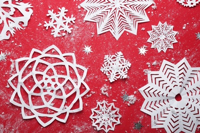 Photo of Flat lay composition with paper snowflakes on red background. Winter season