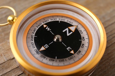 Photo of One compass on wooden table, closeup. Navigation equipment