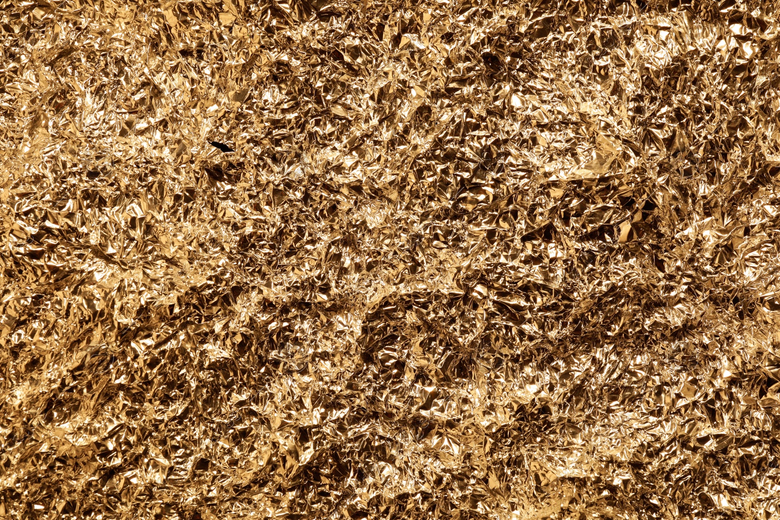 Photo of Crumpled gold foil as background, top view