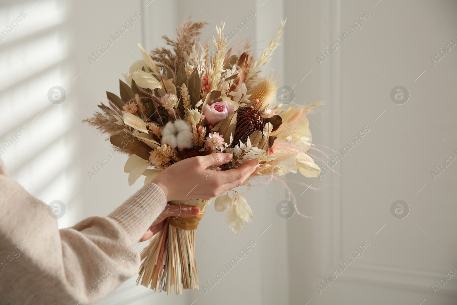 Photo of Woman holding beautiful dried flower bouquet at home, closeup