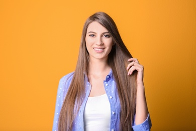 Portrait of young woman with long beautiful hair on color background