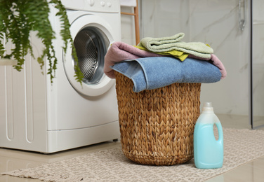 Wicker basket with laundry, detergent and washing machine in bathroom