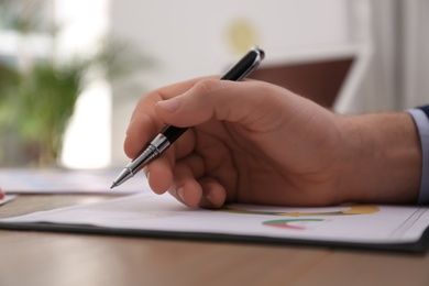 Photo of Businessman working with documents at table in office, closeup. Investment analysis