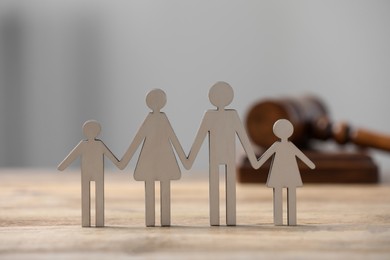 Photo of Family law. Figure of parents with children on wooden table, closeup