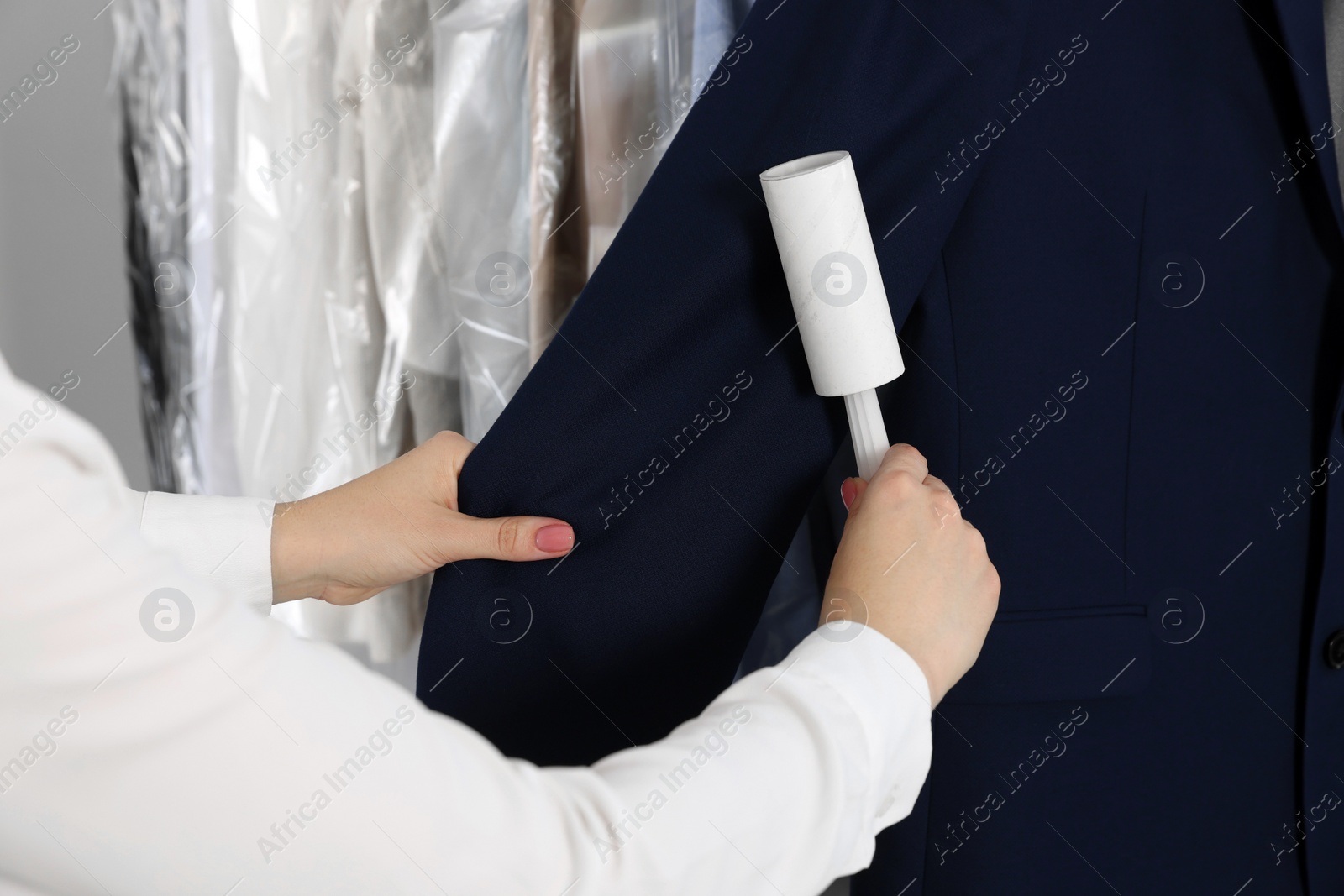 Photo of Woman using adhesive lint roller indoors, closeup. Dry-cleaning service