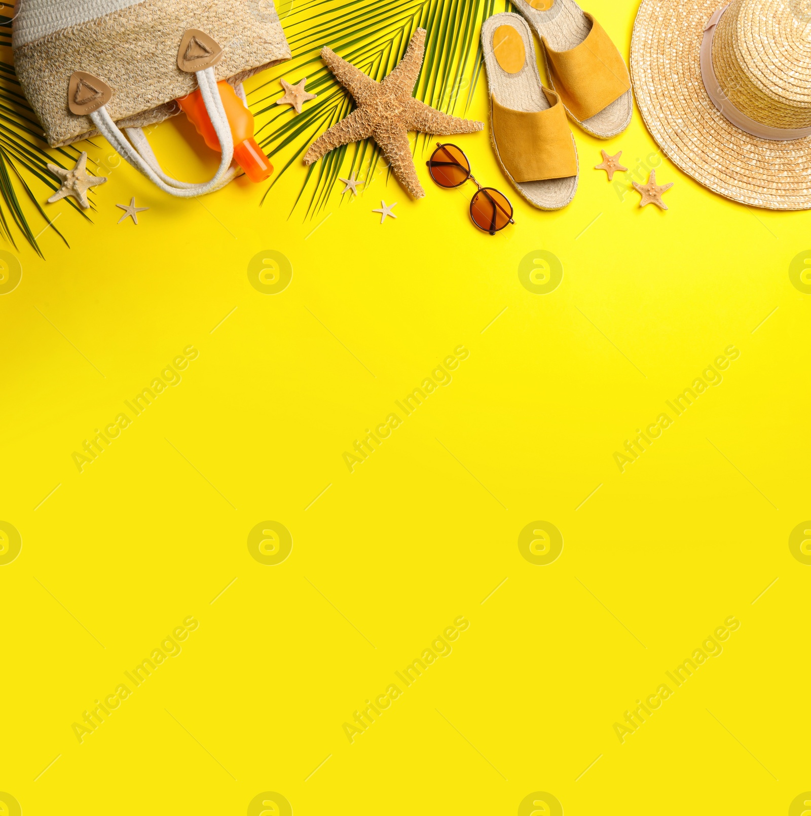 Photo of Beach accessories on yellow background, flat lay. Space for text