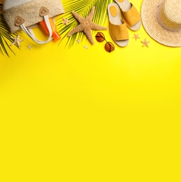 Beach accessories on yellow background, flat lay. Space for text