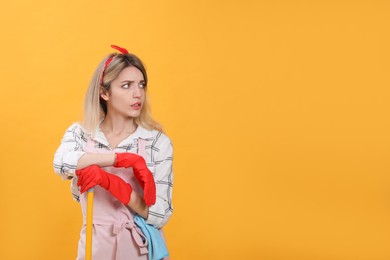 Photo of Young housewife with broom on yellow background. Space for text