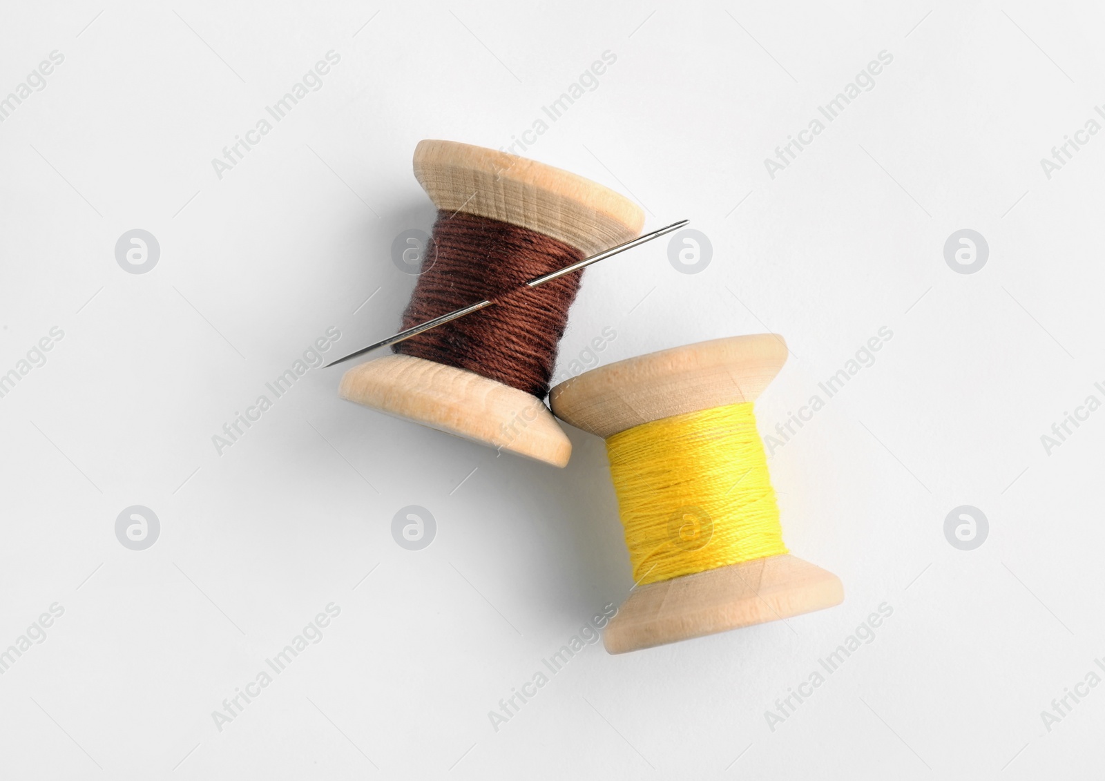 Photo of Colorful sewing threads with needle on white background, top view